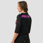 Back view of woman wearing a black 3/4 sleeve activewear top featuring the great walks of New Zealand featuring colourful brushstrokes with each great walk listed.