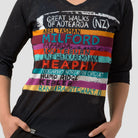 Close up of woman wearing a black 3/4 sleeve activewear top featuring the great walks of New Zealand featuring colourful brushstrokes with each great walk listed.